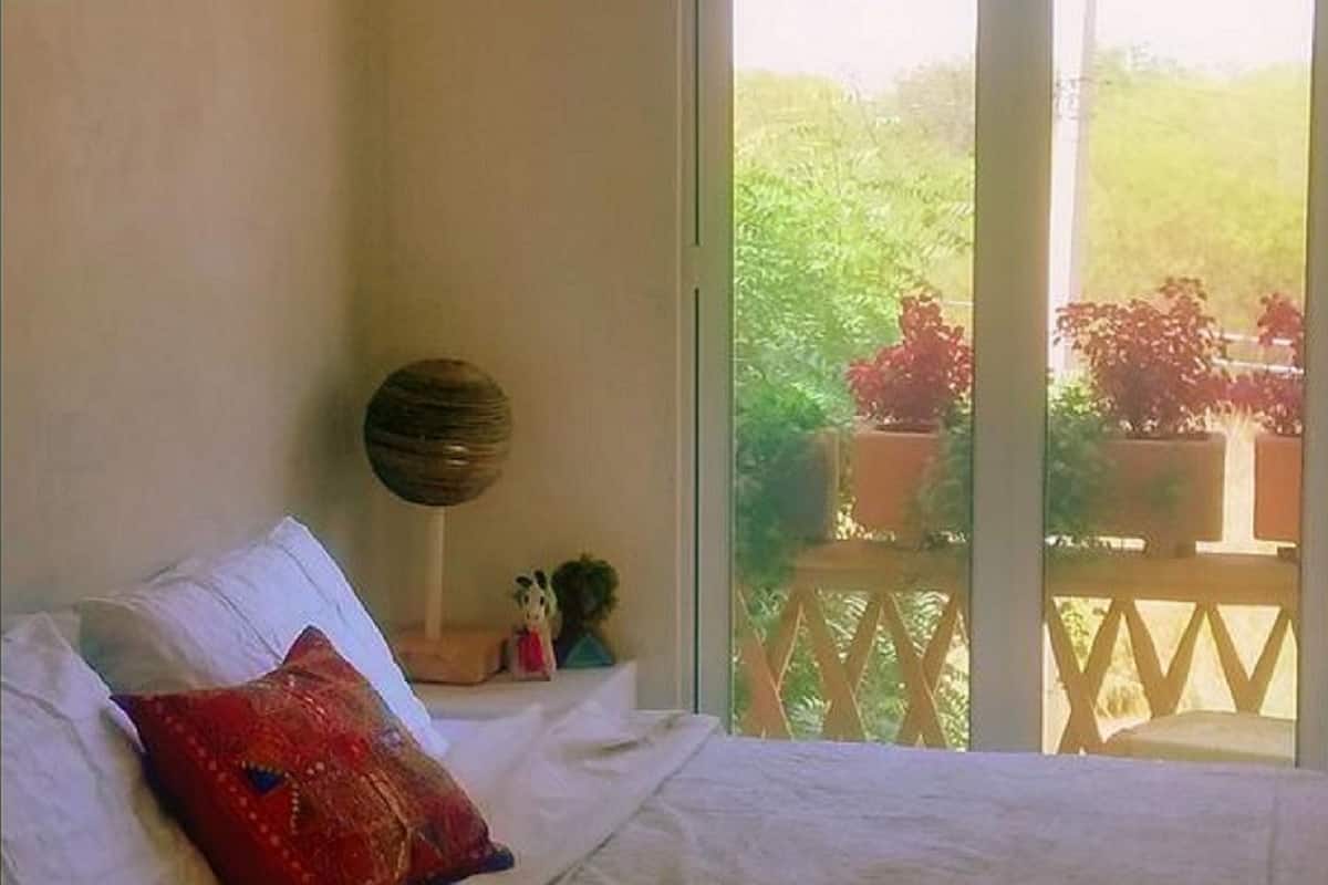 A bedroom with a bed, a round wall decoration, and a view of a garden through a sliding door.
