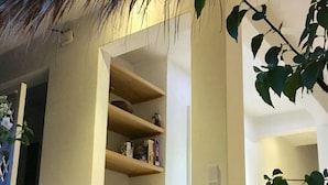 Un interior moderno con techo de paja, estantes de madera y un sofá blanco.