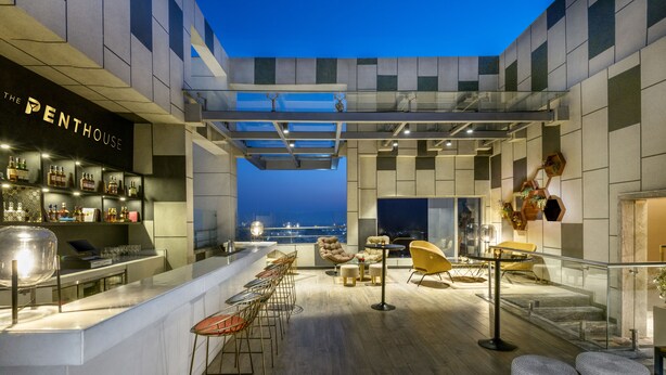 A rooftop bar with a bar counter, seating area, and a view of the cityscape at dusk. - Hyatt Regency Lucknow (Lucknow)