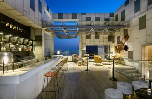 A rooftop bar with a bar counter, seating area, and a view of the cityscape at dusk. - Hyatt Regency Lucknow (Lucknow)