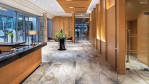 A modern hotel lobby with a marble floor, wooden reception desk, and large windows offering views of the outdoors. - Hyatt Regency Lucknow (Lucknow)