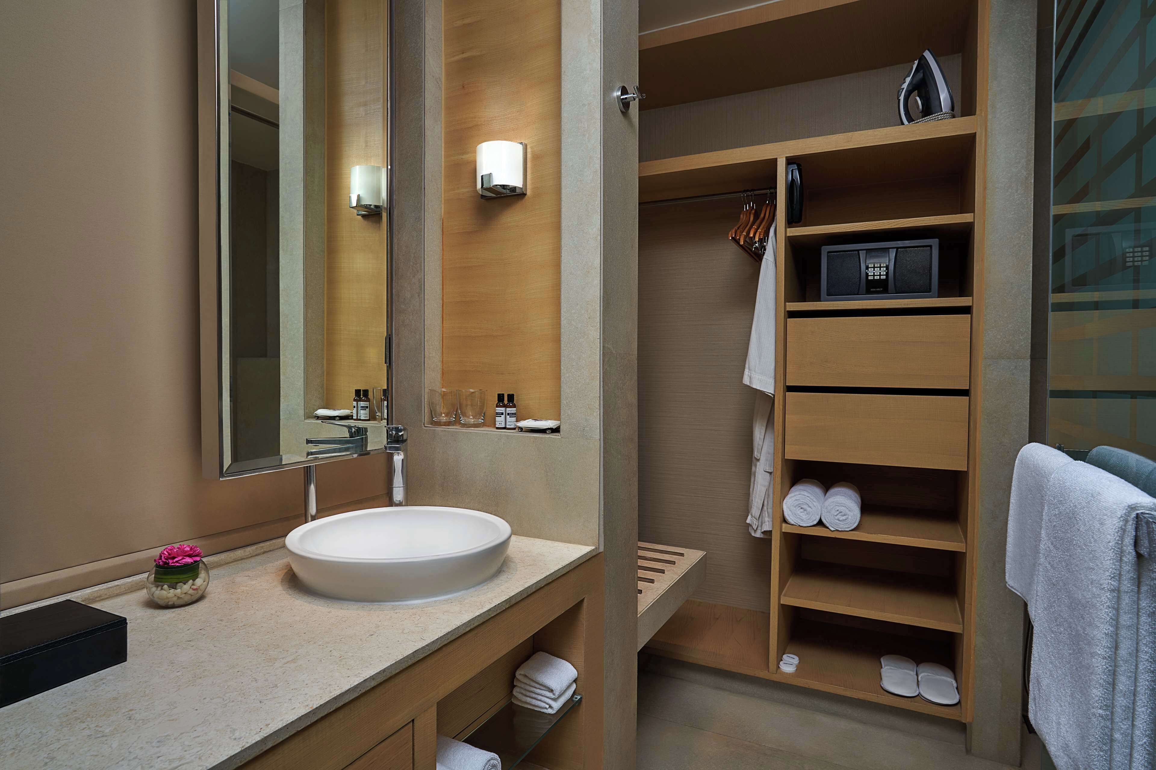 A modern bathroom with a large mirror, a round sink, and a wooden vanity.