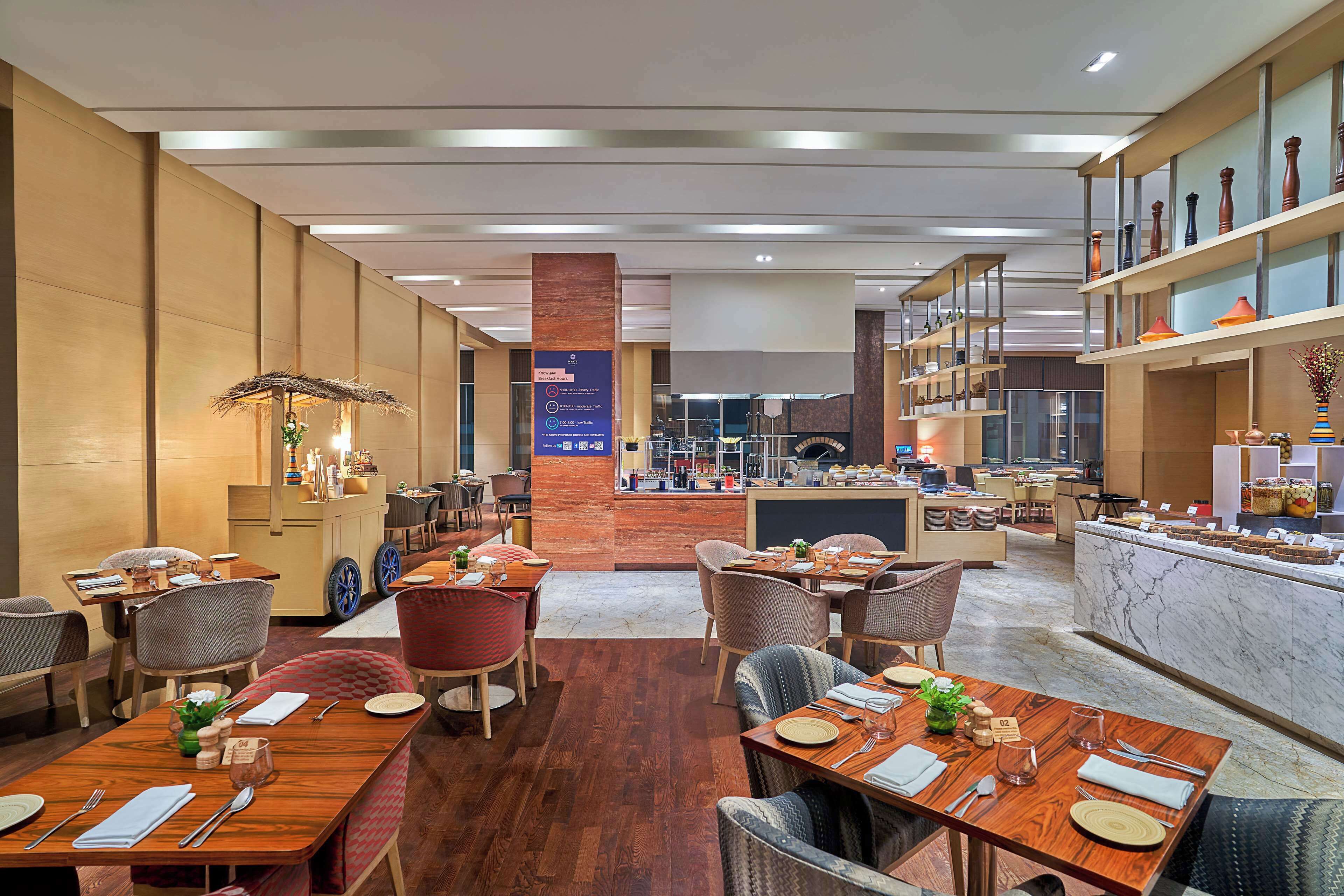 A modern restaurant with wooden tables and chairs, a bar area, and a marble counter.