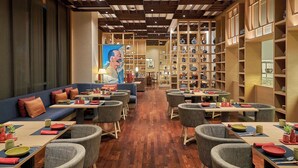 A restaurant with wooden flooring, blue sofas, and round tables with chairs. - Hyatt Regency Lucknow (Lucknow)