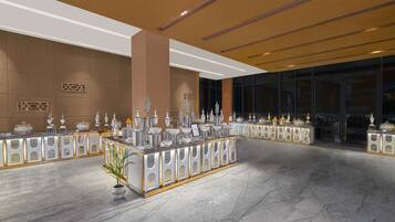 Un vestíbulo espacioso con piso de mármol, una recepción central decorada con trofeos y un amplio ventanal con vistas a la ciudad.