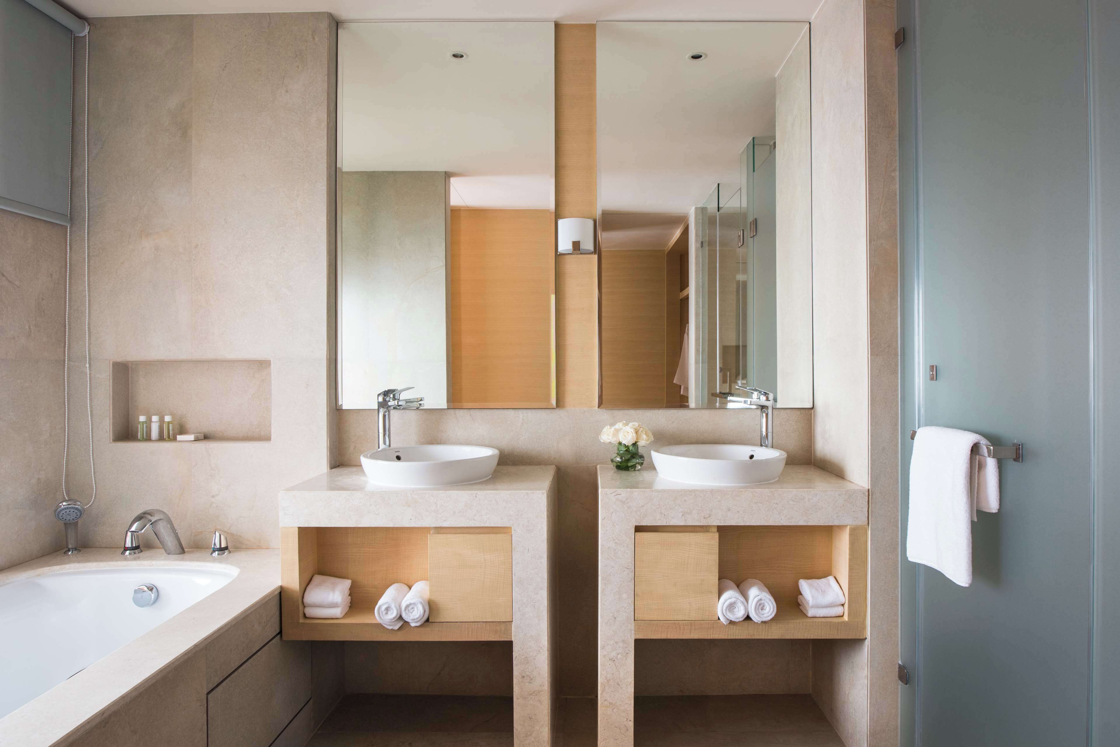 Un baño moderno con dos lavamanos, un espejo grande y un perchero para toallas.