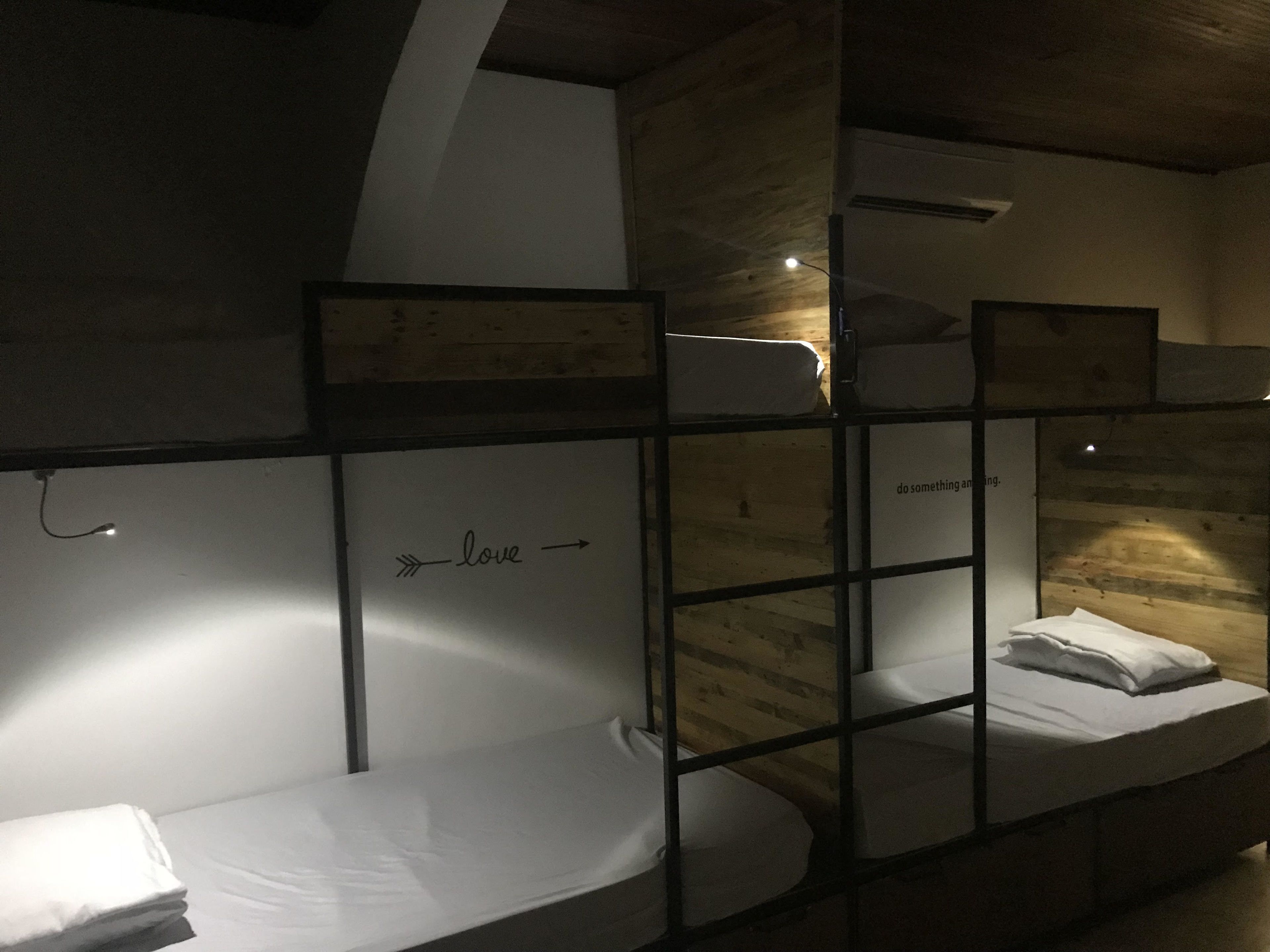 Habitación con literas de madera y un colchón blanco en la litera inferior.