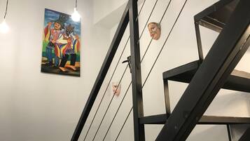 Stunning staircase with a handrail, light fixtures, and artwork adorning the walls.