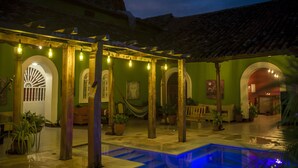 Un patio con piscina, paredes verdes y pilares de madera.