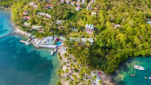 Vue aérienne d’une station balnéaire comprenant plusieurs bâtiments, une plage et des bateaux.