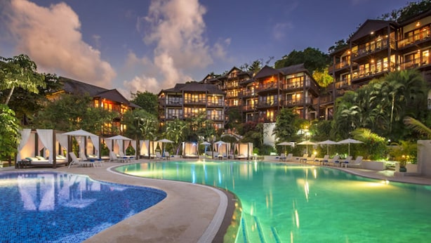 Un complexe hôtelier doté d’une grande piscine, de plusieurs villas pour les clients et d’une végétation luxuriante.