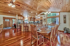 A spacious kitchen with wooden cabinets, a large island, and a dining area with wooden chairs and a table. - 4000 Sq Ft Luxury Home: Family and Pet-friendly, Enormous Game Room, EV Charger (South Lake Tahoe)