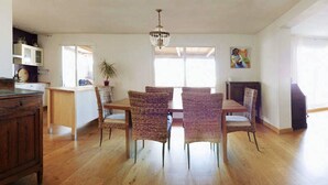A dining area with a wooden table and wicker chairs, a chandelier, and a view of the outdoors through large windows. - Beautiful large 3 bedroom apartment, terrace sea views, Wifi. (Tarifa)
