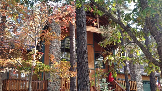A rustic cabin with a stone base, wooden upper structure, and a wooden deck. -  Pinetop CClub, AC, 2 Bd Rm Plus Loft, Huge Windows, Enclosed Deck, 1/2 Acre, (Pinetop)