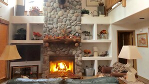 A living room with a stone fireplace, a television, and a sofa. -  Pinetop CClub, AC, 2 Bd Rm Plus Loft, Huge Windows, Enclosed Deck, 1/2 Acre, (Pinetop)