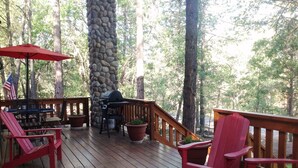 A wooden deck with red chairs, a barbecue grill, and potted plants. -  Pinetop CClub, AC, 2 Bd Rm Plus Loft, Huge Windows, Enclosed Deck, 1/2 Acre, (Pinetop)