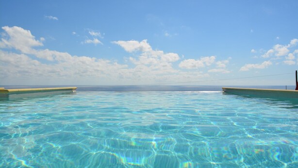 Ein klares, blaues Schwimmbecken mit Blick auf das Meer und den Himmel.