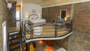 Een slaapkamer met een bed, nachtkastjes, een raam en een bakstenen muur.
