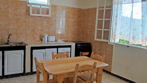A kitchen with a sink, stove, and dining table with chairs. - Superb F3 Apartment with Sea & Mountain View (Souk El Ténine)