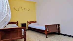 A room with two wooden beds, a yellow wall, and a decorative garland. - Superb F3 Apartment with Sea & Mountain View (Souk El Ténine)