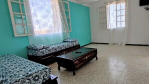 A room with teal walls, a sofa, a coffee table, and a door. - Superb F3 Apartment with Sea & Mountain View (Souk El Ténine)