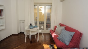 A living room with a red sofa, white curtains, a dining table with chairs, and a radiator. - Jeancarlos House in the historic center (Napoli)