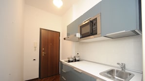A kitchen with a microwave, sink, and wooden door. - Jeancarlos House in the historic center (Napoli)