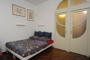 A bedroom with a bed, a wardrobe, and two framed pictures on the wall.