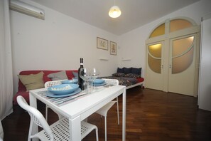 A compact living space with a dining table, chairs, a sofa, and a bed.