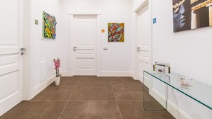 A hallway with white walls, a glass display case, and two paintings. - n'apARTment - art in the heart of Naples (Napoli)