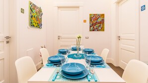 A dining area with a white table set for six, blue tableware, and two abstract paintings on the walls. - n'apARTment - art in the heart of Naples (Napoli)