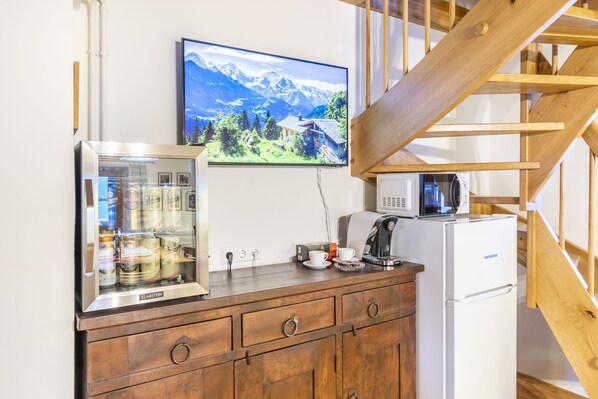 A kitchen with a refrigerator, coffee maker, and a beverage dispenser.