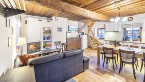 Una sala de estar acogedora con chimenea, un sofá y un comedor con sillas y una mesa.