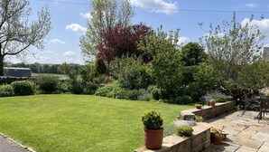 A well-maintained lawn with a stone patio and potted plants. - Characterful , pet friendly cottage ,sleeps 4 ,stunning views ,village location. (Biggin)
