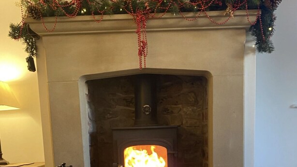 A cozy room with a fireplace, a tray with white teacups and a teapot, and plates with food. - Characterful , pet friendly cottage ,sleeps 4 ,stunning views ,village location. (Biggin)