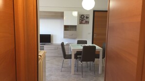 Una cocina moderna con comedor, televisor y puerta que da a otra habitación.