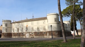 Ein historisches Gebäude mit Innenhof, einem runden Turm und einer symmetrischen Fassade mit zahlreichen Fenstern.