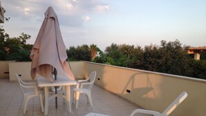Une terrasse avec une table et des chaises, un parasol et un transat.