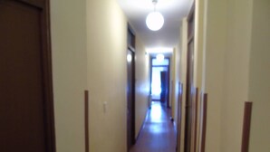 Een smalle, zwak verlichte gang met een plafondlamp aan het einde.