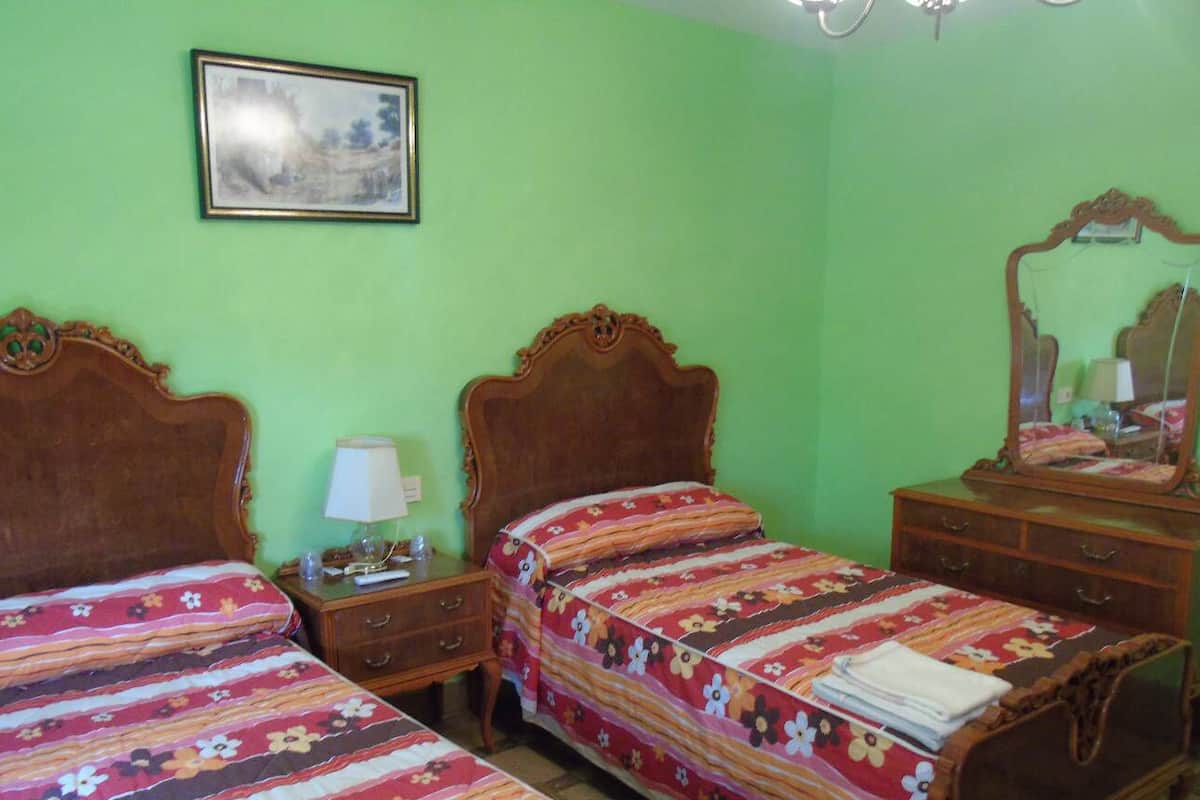 Una habitación con dos camas, un aparador, una mesita de noche, una lámpara y un espejo.