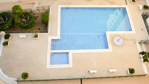 Vue aérienne d’une piscine sur le toit, avec une petite piscine attenante, le tout entouré de plantes en pot et agrémenté de quelques coins salon.