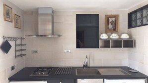 A modern kitchen with a gas stove, stainless steel sink, and a black backsplash. - Detached house in a lovely historic center in Pisticci (Pisticci)