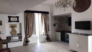 A modern living room with a dining area, a kitchen, and a TV mounted on the wall. - Detached house in a lovely historic center in Pisticci (Pisticci)