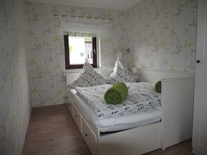 Une chambre à coucher avec un lit, du linge de lit blanc et des oreillers verts.