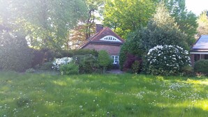 A house surrounded by lush greenery and flowering bushes. - Morning sun vacation apartment in a country house with a magnificent garden  (Westerstede)