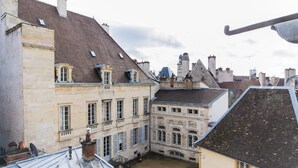 Une cour bordée de bâtiments aux façades en pierre et aux toits en pente.