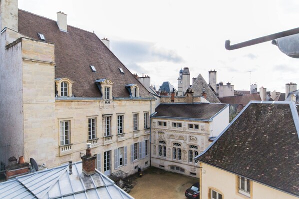 A courtyard with buildings featuring stone facades and pitched roofs.