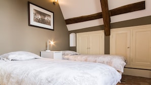 Une chambre avec deux lits, une table de chevet, une lampe de chevet et un tableau encadré au mur.