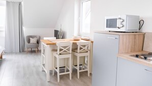 Cozinha moderna com micro-ondas, bancada de madeira e área de jantar com duas cadeiras.