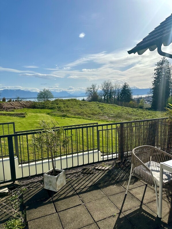 A patio with a view of a grassy area and mountains in the distance. - Get up with SEEBLICK style apartments mountain and lake view and terrace in Lindau (Lindau (Bodensee))